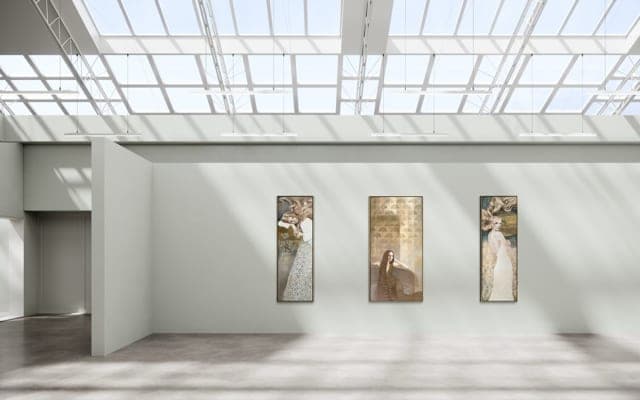 Three tall panels hung in a daylit gallery under a glass roof.